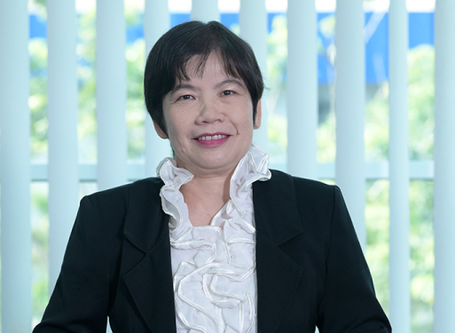 Frau Chan Saw Kuan mit dunklem Anzug und weißem Hemd vor vertikalen, hellen Lamellen sitzend.