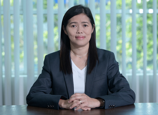 Frau Agnes Cheong mit dunklem Anzug und weißem Hemd vor vertikalen, hellen Lamellen sitzend.