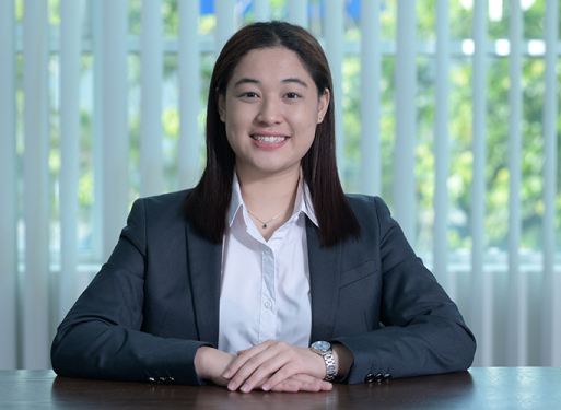 Frau Angel Lim mit dunklem Anzug und weißem Hemd vor vertikalen, hellen Lamellen sitzend.