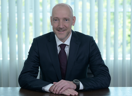 Herr Joerg Tigges in dunklem Anzug mit Krawatte