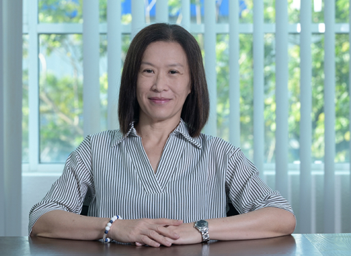 Frau Lim Sook Shun in hellem gestreiften Hemd vor vertikalen Jalousien