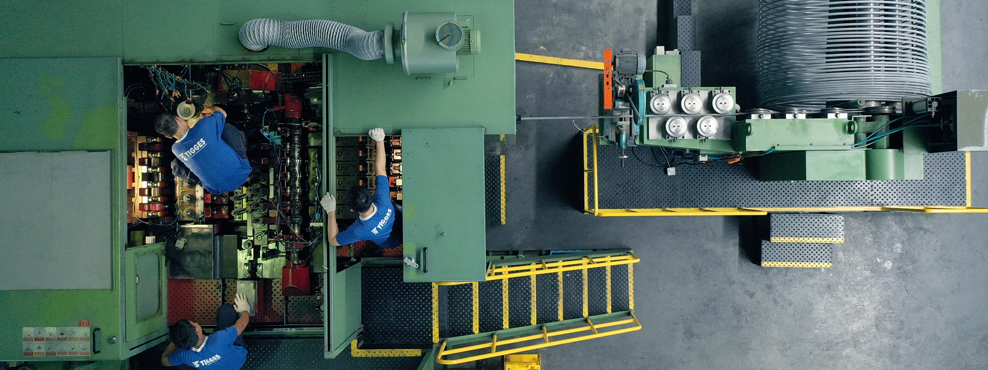 Draufsicht auf Mitarbeiter an einer industriellen Anlage zum Kaltumformen und Fließpressen von Metalldraht in der Fertigung.