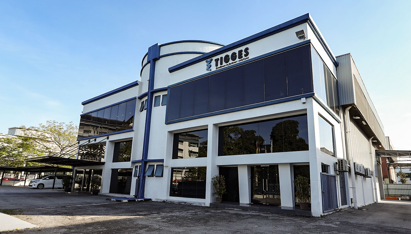 Außenansicht des TIGGES-Unternehmensgebäudes mit moderner Fassade, Büro- und Produktionsbereich an einem sonnigen Tag.